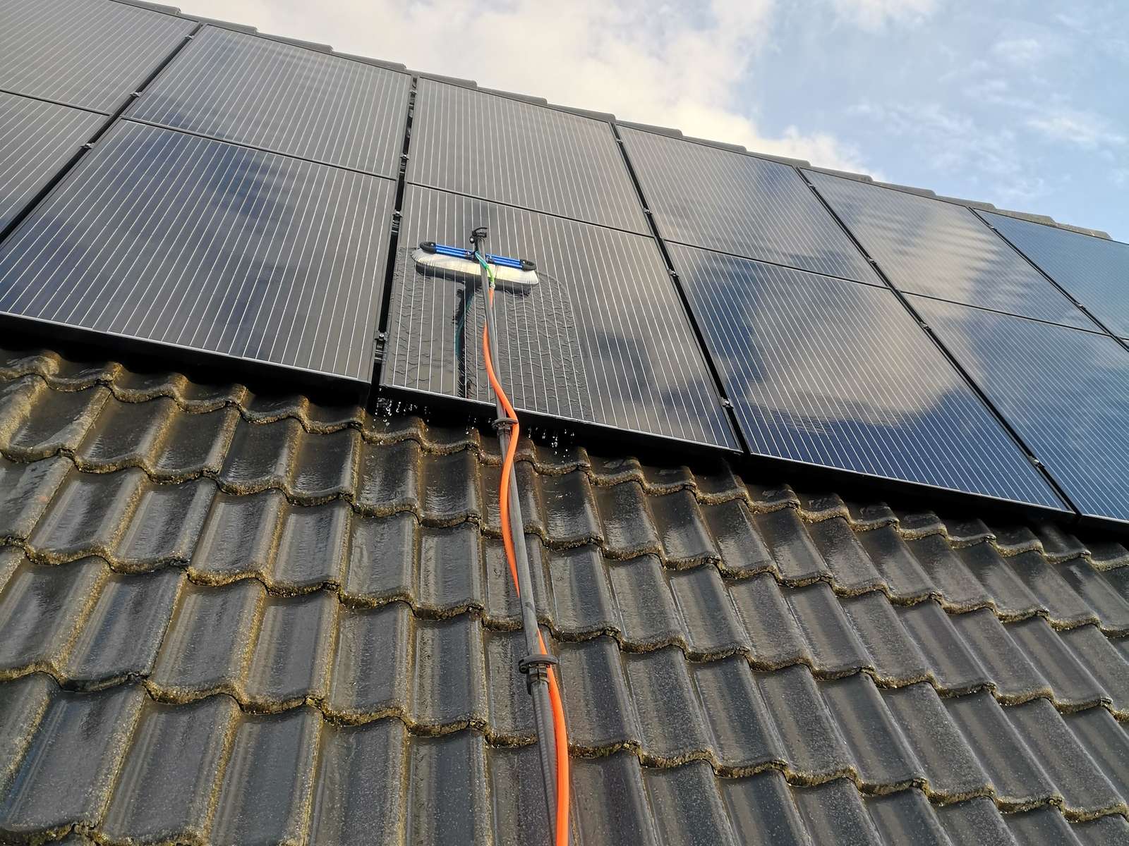 Zonnepanelen op een pannendak met reinigingsborstel